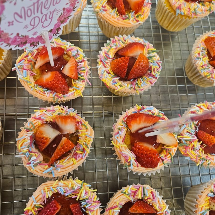 Decorated celebration cupcakes topped with fresh strawberries